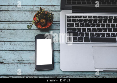 Laptop und Smartphone und Kaktus auf einem Holztisch. Vintage tone Stockfoto