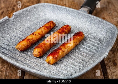 Kupaty in einer Pfanne auf einem Holztisch. Würstchen grillen. Leckeres Essen. Stockfoto