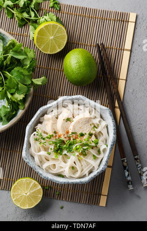 Vietnamesische Suppe Pho Ga mit Hühnchen, Reis Nudeln und frischen Kräutern in eine Schüssel geben. Stockfoto