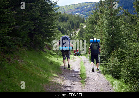 Abenteuer, Reisen, Tourismus, Wandern und Menschen Konzept - Gruppe von Freunden zu Fuß mit Rucksäcken aus zurück Stockfoto