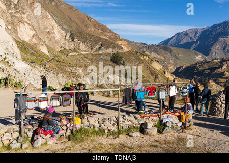 Lokale Damen verkaufen gewebten und gewirkten bunte Kleidung an einem Aussichtspunkt entlang des Randes der Colca Canyon, Peru, Südamerika Stockfoto