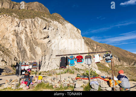 Lokale Damen verkaufen gewebten und gewirkten bunte Kleidung an einem Aussichtspunkt entlang des Randes der Colca Canyon, Peru, Südamerika Stockfoto