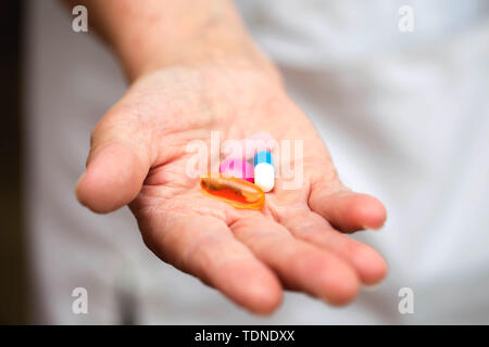 Viele bunte Pillen in einer Obersten Hände. Schmerzhafte Alter. Die Sorge um die Gesundheit der älteren Menschen Stockfoto