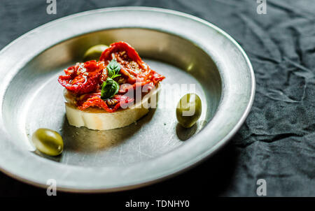 Spanische Tapas Sandwich mit getrockneten Tomaten, Oliven und Basilikum Stockfoto