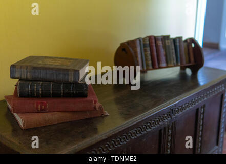 Ein Stapel alter Bücher sitzt auf einem alten hölzernen Stamm Stockfoto