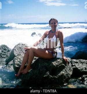 Die deutsche Fernsehmoderatorin, Programmsprecherin, Plant und ehemalige Miss World Petra Schürmann posiert im Urlaub am Strand in Klippen im Bikini, Ca. 1978. Die deutsche TV-Moderatorin, Programm Ansager, Schauspielerin und ehemalige Miss World Petra Schürmann Posen am Strand auf Felsen in einem Bikini, ca. 1978. Stockfoto