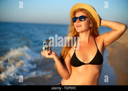 Junge Frau mit Vintage Retro Film Kamera mit tropischen Strand im Sommerurlaub. Weibliche Körper positive Fotograf im Bikini Badeanzug unter Stockfoto