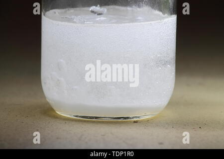 Nahaufnahme einer Essig und Backpulver Reaktion in der Unterseite von einem Glas geschieht; Lösung trüb Stockfoto