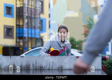 Junge europäische Frau Tischtennis spielen im Hof Stockfoto