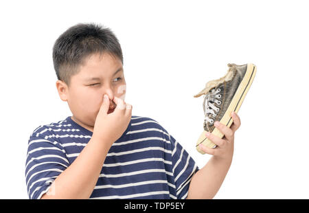 Fat Boy Holding ein Paar muffig und stinkig Schuhe auf weißem Hintergrund angewidert, Stockfoto