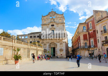 Syrakus, Sizilien, Italien - Apr 10 2019: Leute, die auf der Piazza Duomo Platz vor der beeindruckenden Santa Lucia Alla Badia Kirche. Beliebtes Touristenziel. Sightseeing. Stockfoto