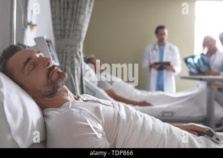 Männliche Patienten schlafend auf dem Bett in der Gemeinde Stockfoto