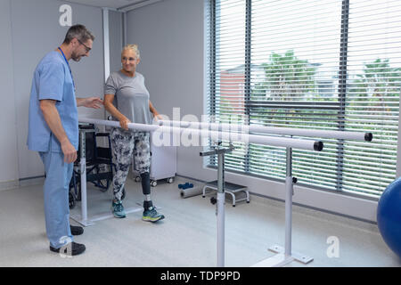 Männliche Physiotherapeuten helfen Patienten mit parallel Bars Stockfoto