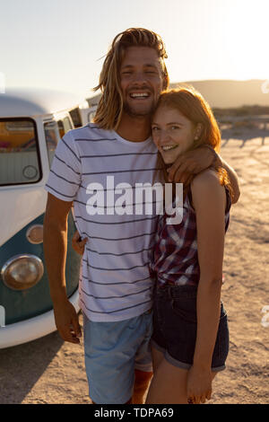 Glückliches junges Paar einander umarmen in der Nähe von Camper am Strand Stockfoto