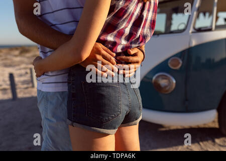 Junge Paare, die in der Nähe von Camper am Strand Stockfoto