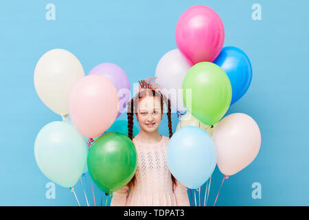 Taille bis Portrait von niedlichen rothaarigen Mädchen, dass Ballons gegen Pastell-blaue Hintergrund stehend, Geburtstag Konzept, kopieren Raum Stockfoto