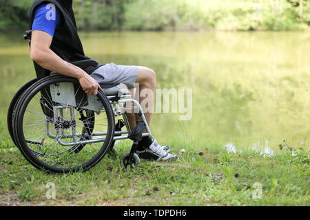 Glücklich und junge behinderte Mann sitzt auf einem Rollstuhl in der Natur. Stockfoto