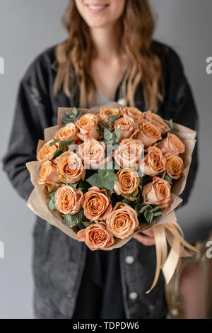Blumen Kaffee, Cappuccino Rosen mit Eukalyptus. Kleine schöne Blumensträuße in der Frau die Hand. Blumen Shop Konzept. Blumen Lieferung Stockfoto