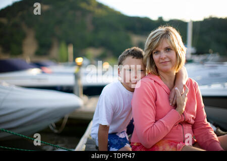 Porträt einer Mutter und ihrem Sohn in der Nähe von angelegten Boote auf einem Steg sitzen. Stockfoto