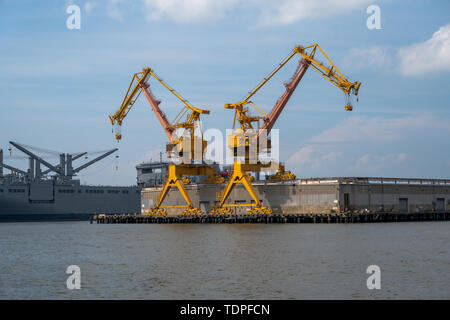 Norfolk, VA, USA - Juni 6, 2019. Foto von einem passenden Paar gelbe Werft Kräne gegen den blauen Himmel im Hafen Virginia, Norfolk. Stockfoto