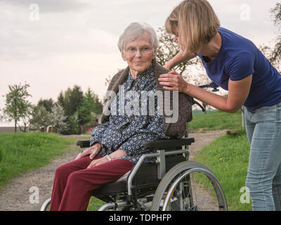 Betreuer hilft besorgt, älteren Dame im Rollstuhl Stockfoto