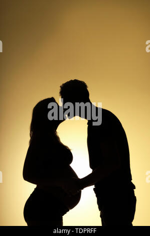 Eine Silhouette in einem Studio von ein paar Küssen, die ein Baby und die Mutter ist gut in ihrer Schwangerschaft; Edmonton, Alberta, Kanada Stockfoto