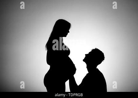 Eine Silhouette in einem Studio der Paare, die ein Baby und der Vater ist berührend Bauch der Mutter, die ist gut entlang in ihrer Schwangerschaft Stockfoto