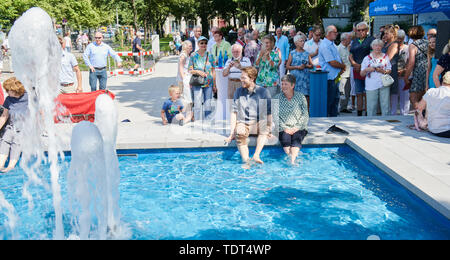 Berlin, Deutschland. Juni, 2019 18. Florian Schmidt (Bündnis 90/Die Grünen), Landrat Friedrichshain-Kreuzberg (l) und Katrin Lompscher (Die Linke), Senatorin für Stadtentwicklung, sitzen an der Quelle und ihre Füße im Wasser halten. Der Brunnen in der Karl-Marx-Allee ist wieder in Betrieb zum ersten Mal nach 27 Jahren der Dürre. Quelle: Annette Riedl/dpa/Alamy leben Nachrichten Stockfoto