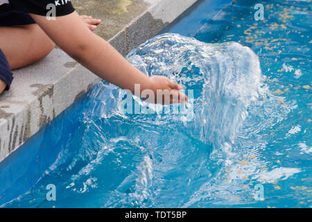 Berlin, Deutschland. Juni, 2019 18. Ein Kind spielt mit seiner Hand in das Wasser aus einem Brunnen. Die drei Brunnen auf der Karl-Marx-Allee wurden heute in Betrieb genommen zum ersten Mal nach 27 Jahren der Dürre. Quelle: Annette Riedl/dpa/Alamy leben Nachrichten Stockfoto
