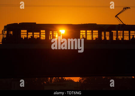 Magdeburg, Deutschland. Juni, 2019 18. Eine Straßenbahn überquert eine Brücke bei Sonnenaufgang und bringt die ersten Pendler in die Innenstadt. Die Region rund um die Landeshauptstadt ist mit einem warmen, sonnigen Sommertag. Es ist heiss. Am späten Nachmittag sollte die Temperatur über 30 Grad Celsius liegen. Credit: Klaus-Dietmar Gabbert/dpa-Zentralbild/ZB/dpa/Alamy leben Nachrichten Stockfoto