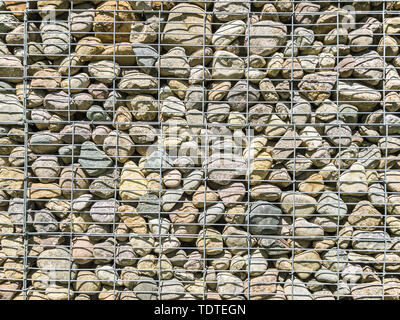 Gabionen wand Muster. Metallgitter mit Viele runde Steine innen Stockfoto