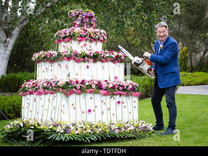 TV Gärtner Alan Titchmarsh vorgibt, riesige dreistufige Blumen Geburtstag Kuchen zu schneiden mit einer Kettensäge bis 70 Jahre der RHS Garden Harlow Carr Mark, während der RHS Garden Harlow Carr Flower Show in Harrogate, North Yorkshire. Stockfoto