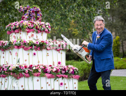 TV Gärtner Alan Titchmarsh vorgibt, riesige dreistufige Blumen Geburtstag Kuchen zu schneiden mit einer Kettensäge bis 70 Jahre der RHS Garden Harlow Carr Mark, während der RHS Garden Harlow Carr Flower Show in Harrogate, North Yorkshire. Stockfoto