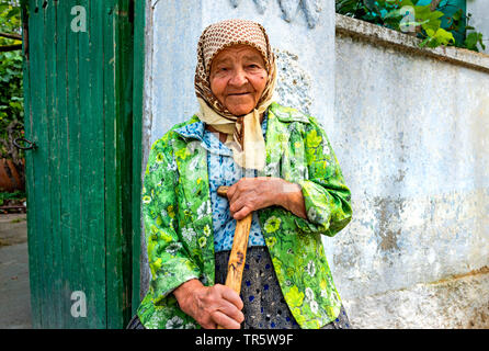 Alte Frau mit Stock vor dem Gartentor, Moldau, Delacau Stockfoto