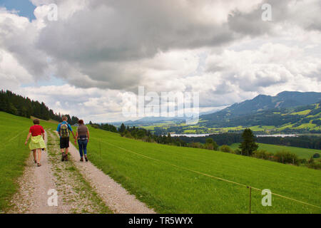 Drei Wanderer auf dem Feld Pfad, See Gruentensee im Hintergrund, Deutschland, Bayern, Allgäu. Stockfoto