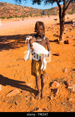 Junge Himba Mädchen tragen ein Lamm, Namibia Stockfoto