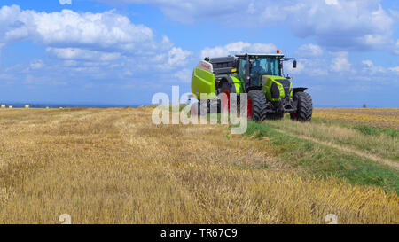 Traktor mit Rundballenpresse auf einem Feld, Deutschland, Nordrhein-Westfalen, Westfalen Stockfoto