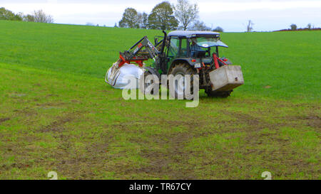 Traktor auf einer Wiese mit Silageballen, Deutschland Stockfoto