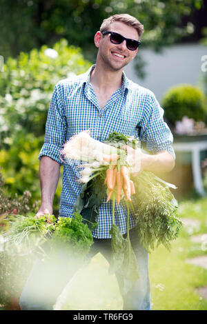 Junger Mann mit Gemüse aus dem eigenen Garten, Deutschland Stockfoto