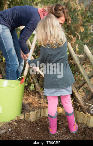 Kleines Mädchen mit rosa Gummistiefel Gartenarbeit mit der Mutter, Deutschland Stockfoto