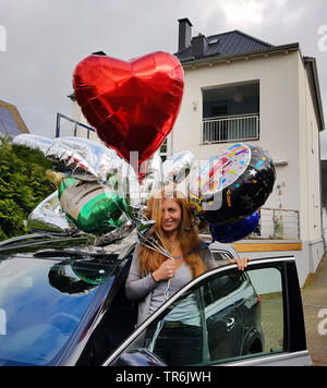 Frau an ihrem Geburtstag mit mehreren Spielzeug Luftballons, nicht in das Auto, Deutschland Stockfoto