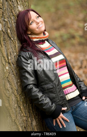 Frau lehnt sich an einem Baum Stockfoto