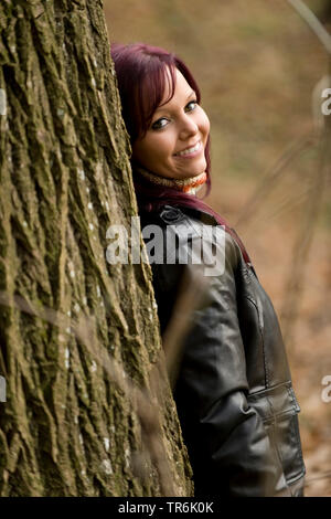 Frau lehnt sich an einem Baum Stockfoto