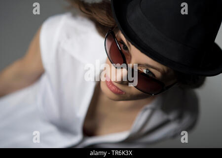 Frau mit Hut und Sonnenbrille im weissen Hemd Stockfoto