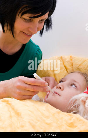 krankes Mädchen n Bett, Mutter mit Fieberthermometer Stockfoto