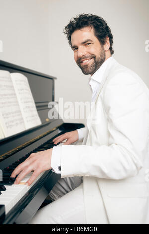 Junger Mann im weissen Anzug an einem Klavier, Deutschland Stockfoto
