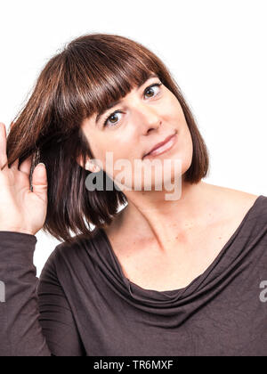 Gut aussehende Frau mit langen braunen Haaren und Fringe mit Hand in das Haar, Deutschland Stockfoto