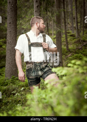 Junger Mann mit bayerische Lederhose wandern im Wald, Deutschland, Bayern Stockfoto