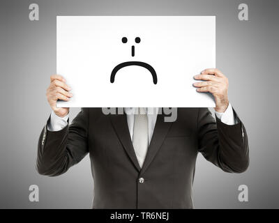 Geschäftsmann mit einem Schild, auf dem eine traurige Smiley, Deutschland Stockfoto