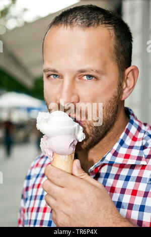 Stattlicher Mann mit Bart ein Eis essen, Deutschland Stockfoto